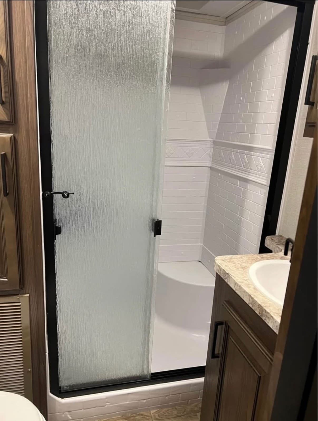 The bathroom in The Crusader with a glass-door shower, a vanity sink with a mirror above it, and a toilet