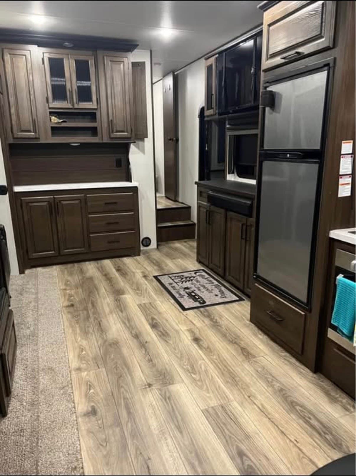 The Crusader looking down the galley toward the carpeted steps up to the queen master suite, with counter and drawers on one side and the refrigerator and oven on the other