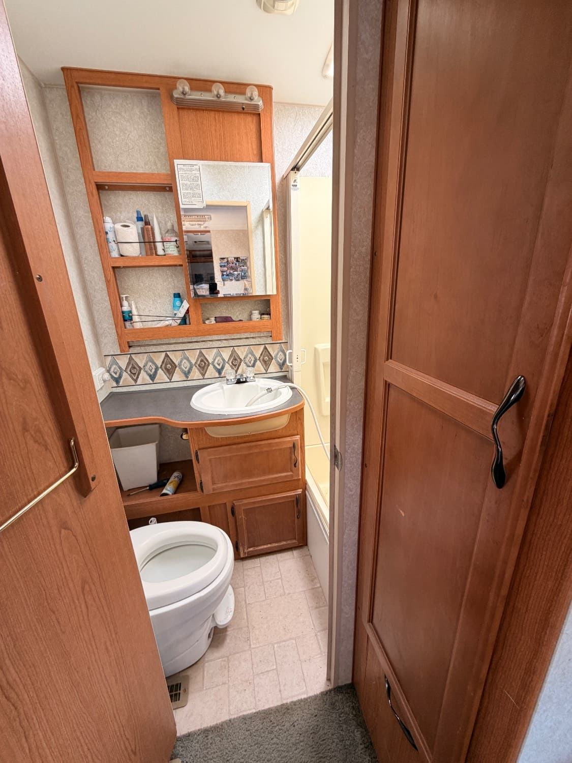 The full bathroom in The Quantum with a toilet, vanity sink, mirrored cabinet and a tub with shower